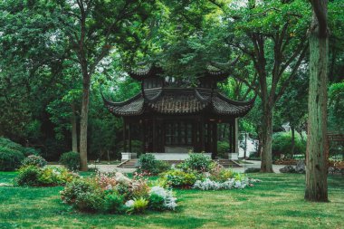 Çin 'in Suzhou şehrinde yemyeşil çimlerle çevrili geleneksel bir Çin bahçe köşkü..