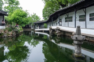 Suzhou, Çin - 11 Haziran 2024: Huzurlu bir gölet Çin 'in Suzhou kentindeki Mütevazı Yöneticinin Bahçesi' nin mimarisini yansıtır.