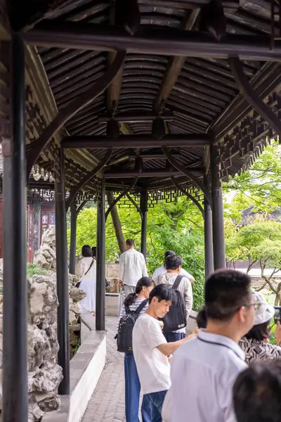 stock image Suzhou, China - June 11, 2024 : A group of people walk through a wooden pavilion in the Humble Administrator's Garden in Suzhou, China.