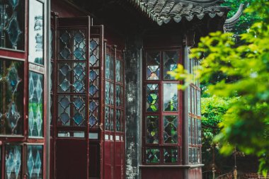 Geleneksel Çin bahçe yapısının yakın plan görüntüsü. Karmaşık bir şekilde oyulmuş ahşap pencereler ve elmas şekilli camlar..