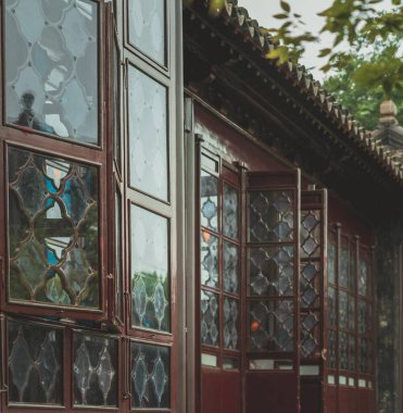 Ahşap pencereler ve karmaşık cam camlar geleneksel Çin mimarisinin arka planına kurulmuş..