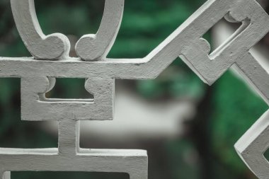 Çin bahçesindeki beyaz, karmaşık bir şekilde oyulmuş, taş bir yapının yakın çekimi..