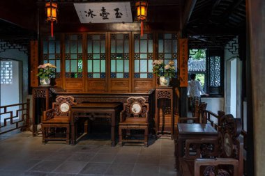 Suzhou, Çin - 11 Haziran 2024: Ahşap mobilyalar ve fenerlerle dolu bir Çin bahçesinde iç mekan.