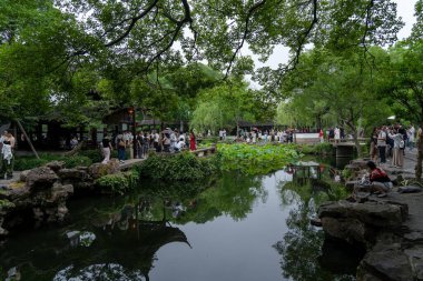Suzhou, Çin - 11 Haziran 2024: Çin bahçesinde bir gölet, bir sürü ağaç, bir çardak, bir köprü ve bir sürü insan.