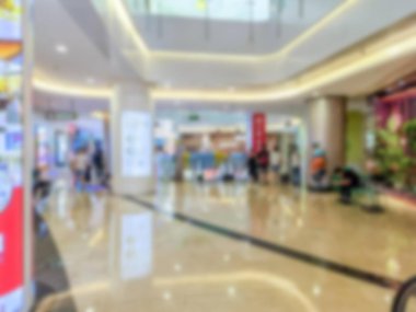 Bir alışveriş merkezinin içi bulanık. Etrafta dolaşan insanlar var..