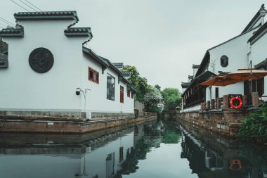 Çin, Suzhou 'da dar bir kanal geleneksel Çin mimarisine sahip iki beyaz bina arasında akar..