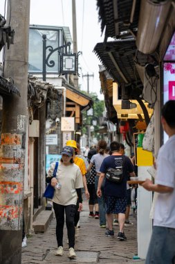 Suzhou, Çin - 11 Haziran 2024: Yayalar Çin 'in Suzhou kentindeki geleneksel Çin binalarıyla çevrili dar bir kaldırım taşı sokakta yürüyorlar.