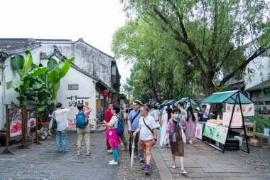 Suzhou, Çin - 11 Haziran 2024: Turistler Çin 'in Suzhou kentindeki dar bir kaldırım taşı caddesinde yürüyor, geleneksel bina ve sokak satıcılarının yanından geçiyorlar..