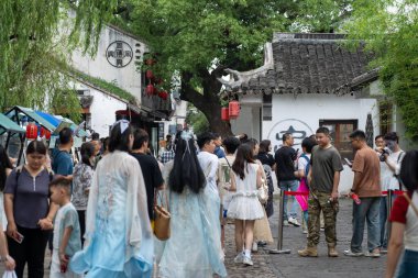 Suzhou, Çin - 11 Haziran 2024: Turistler Çin 'in Suzhou kentindeki geleneksel Çin binalarıyla dolu dar bir kaldırım taşı caddesi boyunca yürüyorlar.