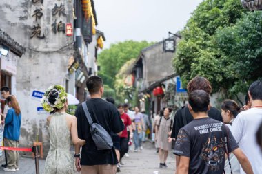 Suzhou, Çin - 11 Haziran 2024: Diğer turistlerle çevrili tarihi bir Çin kasabasında bir çift dar bir sokakta yürüyor.