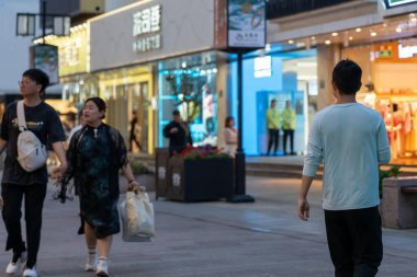 Suzhou, Çin - 11 Haziran 2024: İnsanlar bir kentteki dükkan ve işletmelerin önündeki kaldırımda yürüyor.
