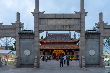 Suzhou, Çin - 11 Haziran 2024: Karmaşık oymalarla dolu geleneksel bir Çin taş kemer yolu, kırmızı fenerler ve hareketli bir pazar içeren bir tapınağı çerçeveler..