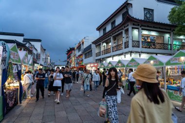 Suzhou, Çin - 11 Haziran 2024: Geleneksel mimari ve insanların alışveriş yaptığı Çin şehrinde hareketli bir sokak pazarı.