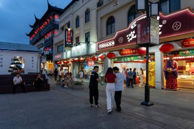 Suzhou, Çin - 11 Haziran 2024: Çin 'in Suzhou şehrinde geleneksel kırmızı fenerler, mağazalar ve kaldırım taşı caddelerinde yürüyen insanlar ile hareketli bir gece pazarı.
