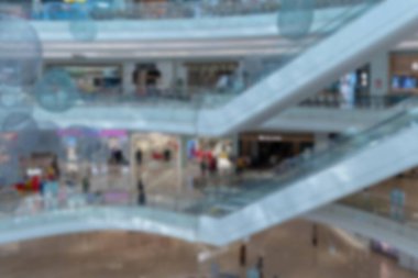 Yürüyen merdivenleri ve beyaz tavanları olan modern bir alışveriş merkezinin bulanık görüntüsü..