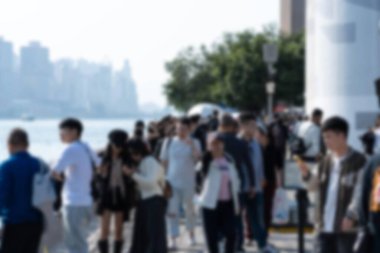 Hong Kong, Çin 'de bir rıhtım boyunca yürüyen turistlerin bulanık bir fotoğrafı. Arkaplanda bulanık bir siluet ve su var..