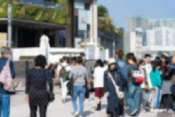 stock image A blurred image of a group of people walking on a sidewalk in front of a building with a green roof.