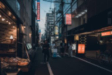 Japonya 'da dar bir caddenin bulanık bir görüntüsü var, arka planı bokeh ve yürüyen insanlar..