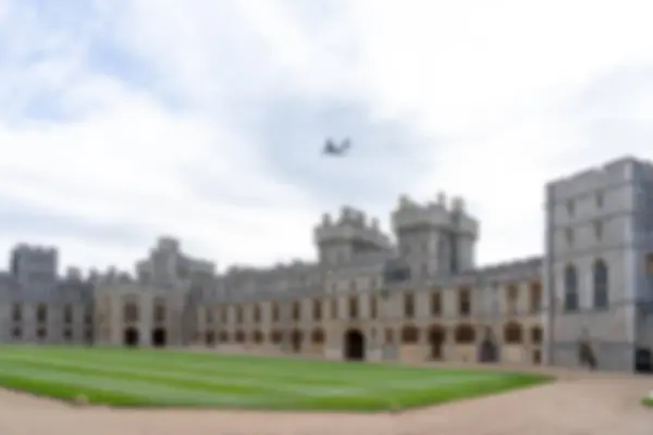 stock image Blurred image of a large stone castle with a lawn in the foreground and a cloudy sky above.