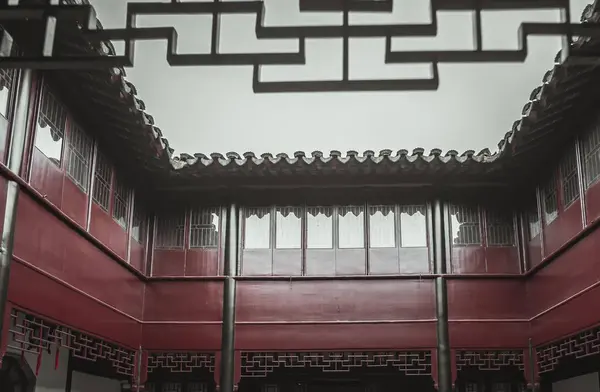 stock image An overhead view of a traditional Chinese courtyard with a red wooden frame and black trim, the sky can be seen through an intricate latticework design at the top.