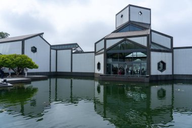 Suzhou, Çin - 12 Haziran 2024: Önünde gölet olan beyaz bir binanın modern mimarisi.