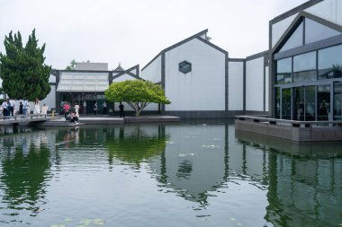 Suzhou, Çin - 12 Haziran 2024: Modern mimari bir müzenin önündeki bir gölete yansıyor..