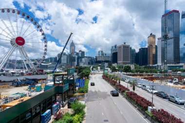 Hong Kong, Çin - 3 Temmuz 2024: Hong Kong, Çin 'de hareketli bir şehir caddesi manzarası, ön planda dönme dolap ve arka planda yüksek gökdelenler.