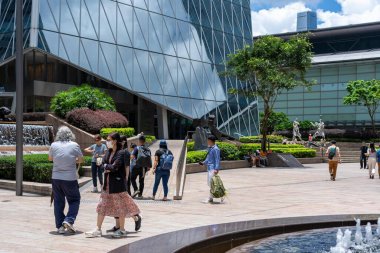 Hong Kong, Çin - 3 Temmuz 2024: Hong Kong, Çin 'de modern bir plaza manzarası. İnsanlar orta alanda heykelleri olan bir çeşmenin yanında yürüyor ve oturuyorlar..