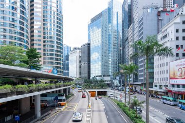 Hong Kong, Çin - 3 Temmuz 2024: Hong Kong, Çin 'de yüksek binalar, palmiye ağaçları ve araçların geçtiği bir sokak manzarası.