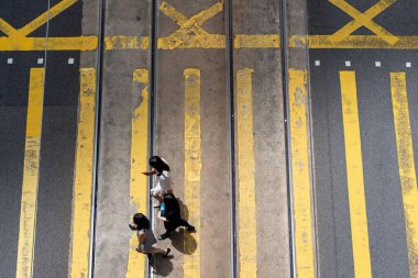 Hong Kong, Çin - 3 Temmuz 2024: Merkez, Hong Kong, Çin 'de üç kişi, tramvay hatları arasında sarı çizgiler üzerinden yürüyorlar..