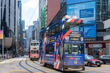 Hong Kong, Çin - 3 Temmuz 2024: Hong Kong 'da yüksek binaların yanından geçen bir futbol maçı reklamı ile süslenmiş bir Hong Kong tramvayı.