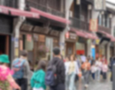 Dükkanlar, insanlar ve Çin 'in Hangzhou kentindeki kırmızı tente ile dolu işlek bir caddenin bulanık fotoğrafı. Arka plan bokeh.
