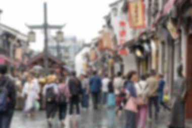 Çin 'in Hangzhou kentindeki işlek bir caddenin bulanık bir görüntüsü. Cadde bina ve dükkanlarla dolu ve insanlar yürüyor ve alışveriş yapıyor. Bokeh etkisi bir hareket ve enerji hissi yaratır..