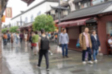 Hangzhou, Çin 'de kalabalık bir caddenin bulanık fotoğrafı. Bokeh efektleri işlek sokak sahnesini vurgular.