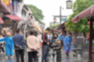 Çin 'in Hangzhou kentindeki bulanık sokak manzarası, dükkanların önünden geçen bokeh ışıkları ve yayalar....
