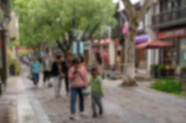 Çin, Hangzhou 'da bir caddenin bulanık görüntüsü, insanların yürüdüğü yeşil ve bokeh.