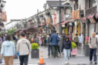 Hangzhou, Çin 'de kalabalık bir caddenin ön planda bir trafik konisiyle bulanık bir fotoğrafı. Sokaklar binalarla dolu ve insanlar her iki yönde de yürüyor..