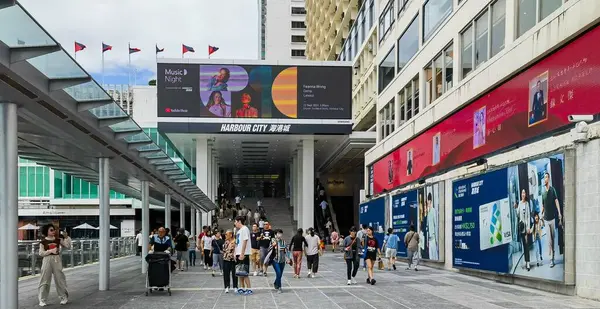 stock image Hong Kong, China - September 18, 2024 : People walk along a sidewalk in Hong Kong, China. They are walking past a large shopping mall.