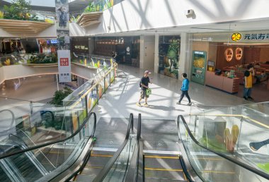 Shenzhen, China - October 25, 2024 : A modern shopping mall in Shenzhen, China, featuring escalators, tiled floors, and large windows. clipart