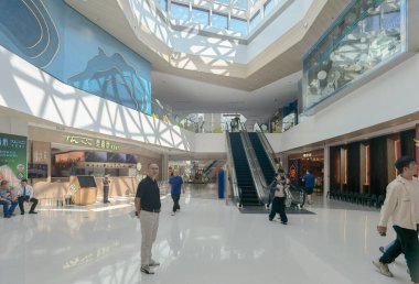 Shenzhen, Çin - 25 Ekim 2024: Beyaz döşemesi, yürüyen merdiveni ve tavan penceresi olan modern bir alışveriş merkezi.