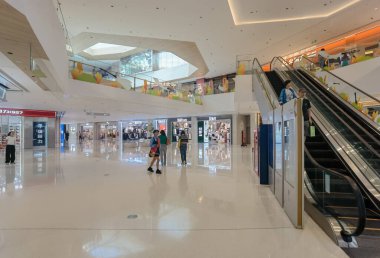 Shenzhen, Çin - 25 Ekim 2024: Beyaz zemini, yürüyen merdivenleri ve müşterileri olan modern bir alışveriş merkezi.