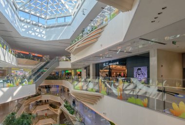 Shenzhen, Çin - 25 Ekim 2024: Yürüyen merdivenleri, tavan penceresinden gelen doğal ışığı ve çağdaş bir tasarımı olan modern bir alışveriş merkezi.