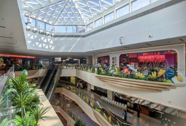 Shenzhen, Çin - 25 Ekim 2024: Çağdaş bir estetik tasarımı sergileyen cam tavanı ve yürüyen merdiveni olan modern alışveriş merkezi iç mimarisi.