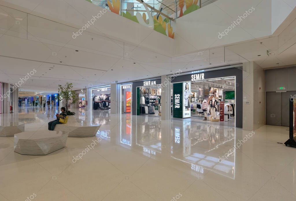 Shenzhen, China - October 25, 2024 : A modern shopping mall in Shenzhen, China with white tiled floors, reflective surfaces and  retail stores.