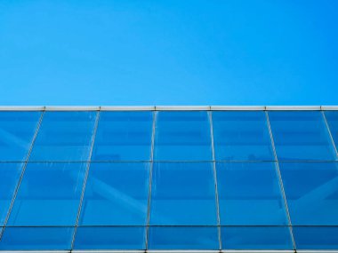 Close-up details of a Hong Kong building's glass facade against a vibrant blue sky.  The intricate structure is visible. clipart