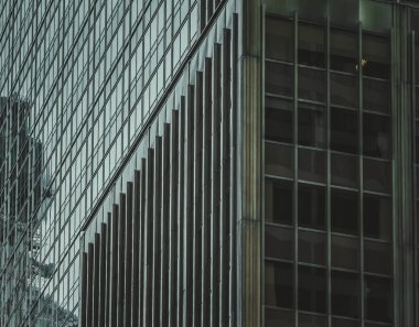 Şık, modern Hong Kong bina cephesi. Geometrik çizgiler ve cam paneller çarpıcı bir mimari ayrıntı yaratır. Işık ve gölgenin etkileşimi dokuyu ve derinliği vurgular.