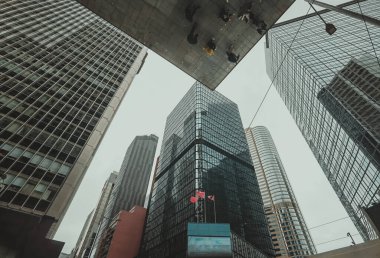Hong Kong 'daki gökdelenlerin alçak açılı görüntüsü, bulutlu bir gökyüzüne uzanan binalar. Şehir sahnesi modern mimarinin yoğunluğunu ve yüksekliğini gözler önüne seriyor..