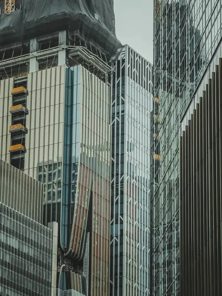 Hong Kong 'un yoğun şehir manzarası, bulutlu bir gökyüzüne doğru yükselen modern binalar kümesi. İnşaat, kentin sürekli büyümesini gösteren bazı yapılarda görülebilir..