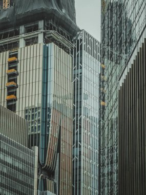 Hong Kong 'un yoğun ve modern gökdelenlerinin yakın görüntüsü. Mimari tarzlar ve inşaat aşamalarının bir karışımı, kentin dikey büyümesini gösteriyor.