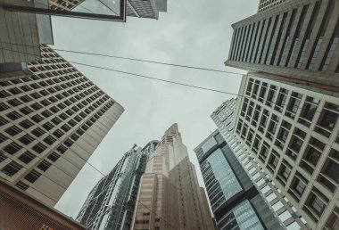 Hong Kong, Çin - 1 Şubat 2025: Düşük açı, Hong Kong 'un merkez iş bölgesindeki gökdelenlerin yakın görüntüsü. Bulutlu gökyüzü yüksek binaları vurguluyor. Seyahat ve iş, şehir manzarası tarafından önerilir..